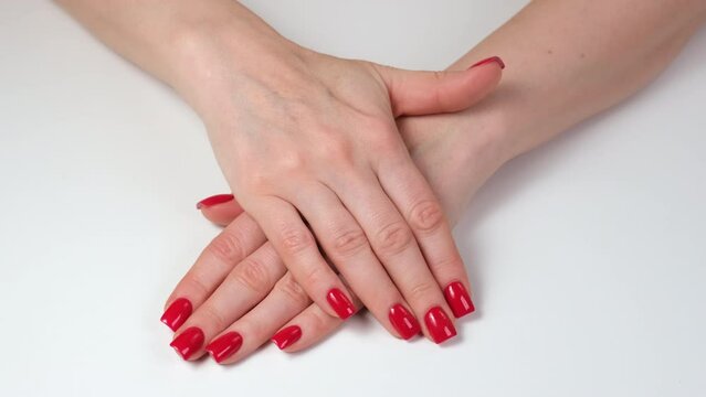 Woman hands with red nails on white table. Top view. Classic manicure