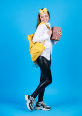 Young smiling woman wearing bow looking back, while carrying yellow backpack. Front view of cute...