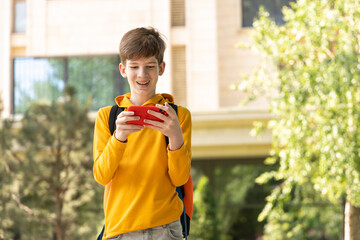 A young boy is having a video call outdoors, holding a smartphone in his hands.