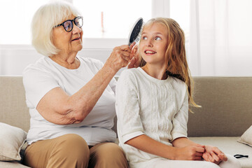 Woman granddaughter girl combing child grandmother love comb couch sofa family home hair happy