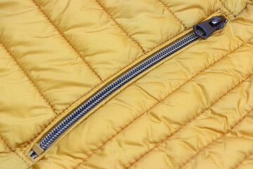Pocket zipper closed on yellow puffer autumn-winter jacket