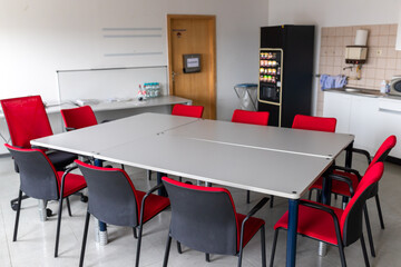 Stühle und Tische mit Kaffeeautomat in einem Pausenraum 