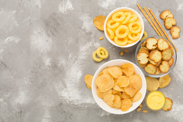 Various unhealthy snacks on concrete background, top view