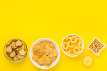 Various unhealthy snacks on color background, top view