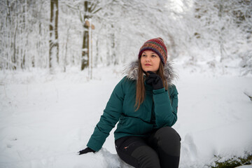 Fototapeta na wymiar Contemplative Woman Seated in a Snowy Forest Setting