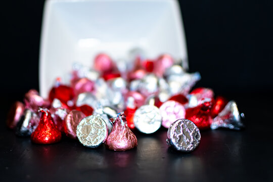 A close up of a white square bowl tipped over spilling candy.