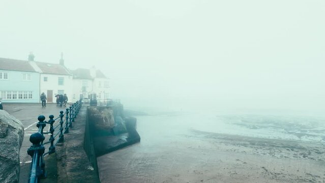People walking along the quite streets of Staithes a sleepy fishing village on the Yorkshire coast of England. With cobbled streets and old stone built houses. Harbor walls and friendly public houses.