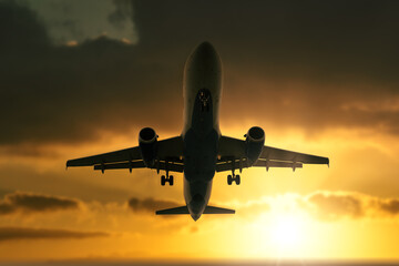 Silhouette of a passenger commercial aircraft against the sunset sky.