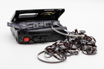 Enredo de casetes de audio magnéticos. Cinta de casete de audio antigua desenrollada sobre fondo...