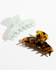 Amber and green plastic hair Claws clips on white background with copy space. Hair accessories.