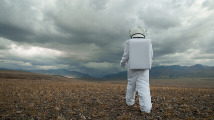 An astronaut explores an unknown planet. Heavy cloudy sky. - 738248242