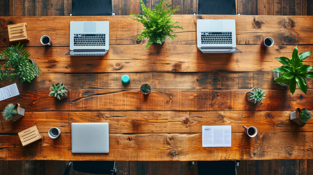 Top view of a wooden communal office table with laptops and plants. Collaborative workspace. Generative AI