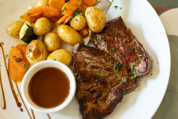 Dish in old bistro in Limoges, France, Limousin cattle beef steak served with oven baked potatos, vegetables and served with light broth or gravy