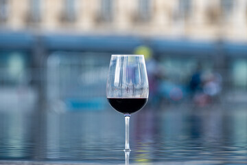Tasting of Bordeaux blended red wine with wine city Bordeaux on background, left bank of Gironde Estuary, France. Glass of red French wine.