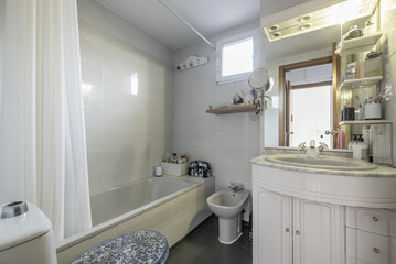 A bathroom furnished a few years ago with white cabinet with sink, mirror and integrated lights