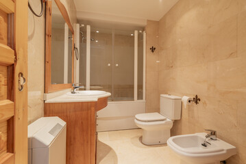 Bathroom, cream marble tile wall, cherry wood cabinet with integrated mirror and sink with marble...