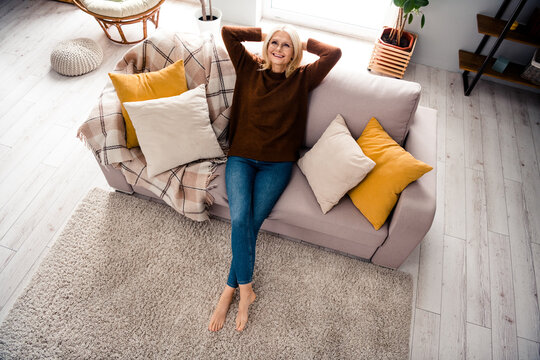 High angle photo of blonde hair mature age woman take nap on gray soft couch relaxing sleepy mood indoors loft modern style living room