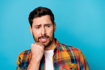 Portrait of confused puzzled guy with stubble wear checkered shirt thoughtfully look empty space isolated on blue color background