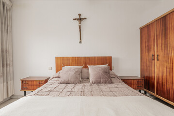 bedroom with varnished wooden headboard and furniture, matching bedspreads and cushions and a...