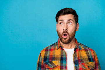 Photo of stunned astonished man with beard dressed checkered shirt staring at proposition empty space isolated on blue color background