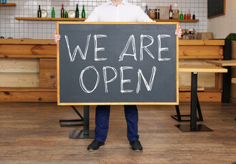 Support local business. We are open. Small business owner holding open sign of restaurant reopening. Entrepreneur opening cafeteria activity to support local businesses