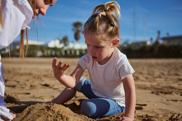 Little girl building sandy castle on the beach