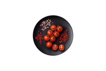 A branch of raw cherry tomatoes with salt and spices on a dark background