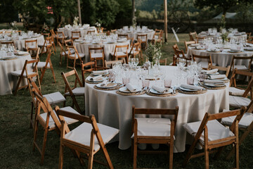 Banquete al aire libre. Mesa redonda decorada en tonos ocres y rosas. Vajilla de porcelana,...