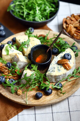 Fototapeta na wymiar Blue cheese with honey, arugula and blueberries. Healthy salad with arugula and dorblu.