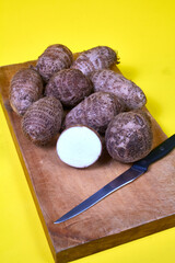 closeup of taro root vegetable, eddo malanga, yellow background