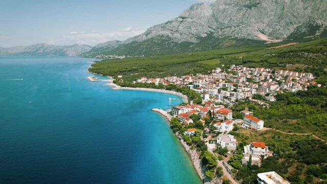 Aerial view of seascape and coastal town Makarska with dense buildings. Majestic Biokovo mountains rise behind, summer landscape in Croatia.