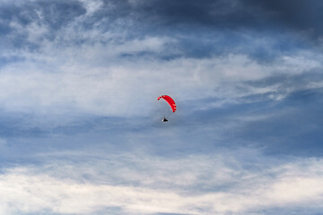 A paraglider soars freely against a backdrop of dramatic clouds, embodying the concept of freedom and adventure. The vast sky accentuates the thrill of flight. Ideal for themes extreme sports