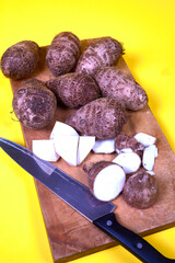 closeup of taro root vegetable, eddo malanga, yellow background