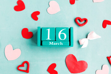 March 16. Blue cube calendar with month date on blue pastel background.