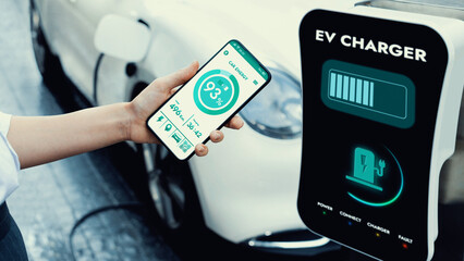 Businesswoman holding smartphone display battery status interface by smart EV mobile application...