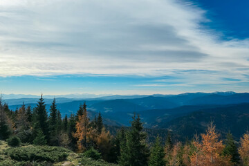 Fototapeta premium Idyllic hiking trail along alpine pasture with panoramic view of mountain ranges of Lower and Higher Tauern seen from Grebenzen, Gurktal Alps, Styria, Austria. Calm serene atmosphere in Austrian Alps