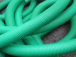 green plastic tube rolled up laying on the sidewalk