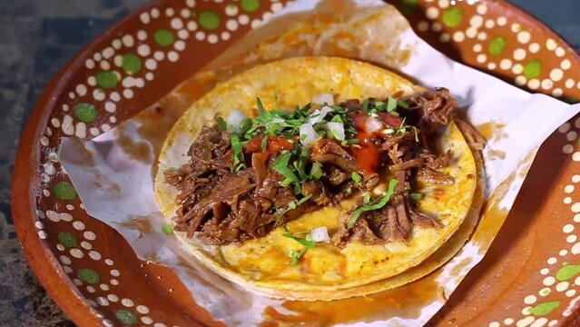Slow motion of person putting cilantro and onion in beef birria taco. Mexican food