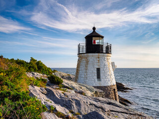 Fototapeta na wymiar Castle Hill Lighthouse in summer overlooking Narragansett Bay, Newport Rhode Island, a beautiful scenic New England landscape. The 1890 light house is built right into the cliff.
