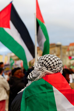 A person wearing Palestinian keffiyeh. Pro-Palestinian protests. Anti-Israel protesters. Palestine Flags. Free Palestine.
