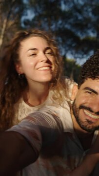 Two lovers smile and take pictures of each other in a forest