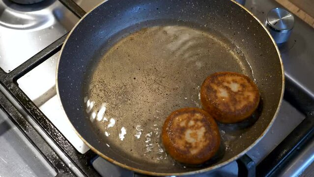 Freshly fried Georgian dish Chadi donuts are removed from a boiling pan with a fork and wooden spoon, high-angle view.