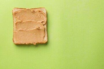 Tasty peanut butter sandwich on light green background, top view. Space for text