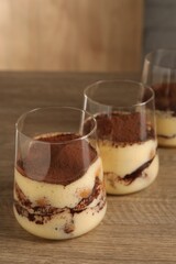 Delicious tiramisu in glasses on wooden table