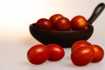 plum tomatoes in a clay dish with white background close up