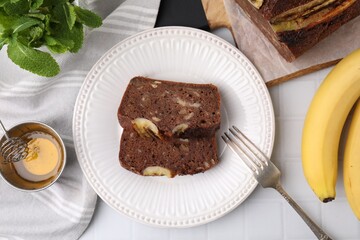 Delicious banana bread served on white tiled table, flat lay