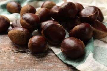 Obraz premium Sweet fresh edible chestnuts on wooden table, closeup
