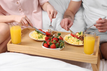 Obraz na płótnie Canvas Couple eating tasty breakfast on bed, closeup