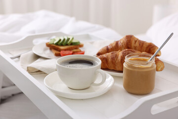 Good morning. Tray with tasty breakfast on bed, closeup