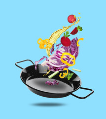 Different vegetables, oil, frying pan in air on light blue background